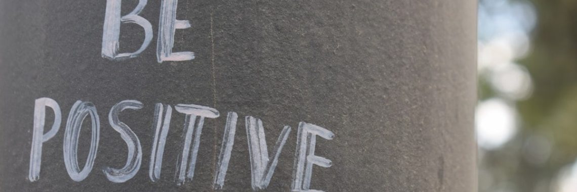 Be positive written on a dark pole.